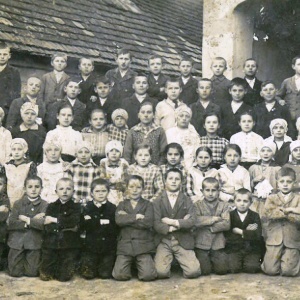 Školsý rok 1925, vpravo pán riaditeľ školy Ján Vojtech. V pozadí s pôvodnou bránou, ktorá bola zborbardovaná počas 2. sv. vojny